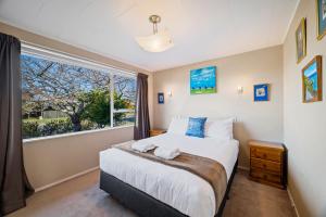 a bedroom with a bed and a large window at Kinder Cottage - Taupo in Taupo