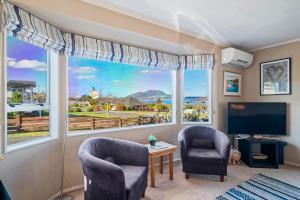 a living room with two chairs and a large window at Kinder Cottage - Taupo in Taupo