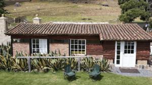 Cabaña Yerbabuena في Toca: منزل صغير أمامه كراسي