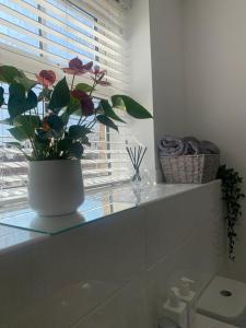 un jarrón con flores sentado en un mostrador en un baño en Central 2-Bed Flat: Ideal for Nurses, Contractors, Relocators - Free WiFi & Parking, en Peterborough