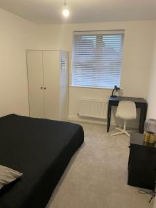 1 dormitorio con cama negra, escritorio y escritorio en Central 2-Bed Flat: Ideal for Nurses, Contractors, Relocators - Free WiFi & Parking, en Peterborough