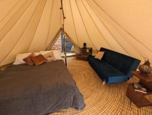 Zimmer mit einem Bett und einem Sofa in einem Zelt in der Unterkunft Glamping Yerbabuena in Toca