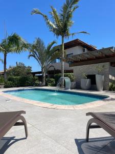 a swimming pool with a fountain and palm trees at Pousada Miradouro in Imbituba