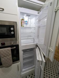 an empty refrigerator with its door open in a kitchen at Fantastic 3-Bedroom House in London in Morden