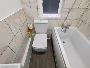 a bathroom with a toilet and a bath tub at Fantastic 3-Bedroom House in London in Morden