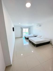 two beds in a room with white tile floors at Hotel AguaMarina Rodadero Santa Marta in Gaira