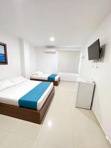 a bedroom with two beds and a tv in it at Hotel AguaMarina Rodadero Santa Marta in Gaira