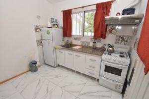 a kitchen with white cabinets and a stove and refrigerator at Kaiken Maison in Villa Santa Cruz del Lago