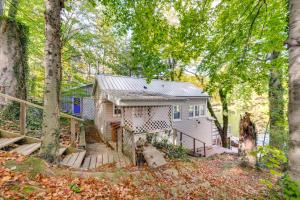 a small white house with a porch in the woods at Horseshoe Lake Vacation Rental with Deck and Kayaks! in Batavia