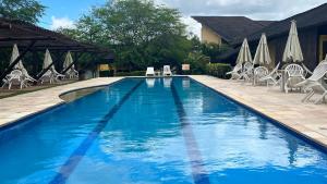 une grande piscine bleue avec des chaises et des parasols dans l'établissement Winterville flat 307, à Gravatá