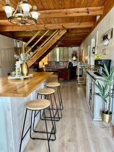 Crane Hill的住宿－Best Life Now Cottage，厨房以及带木制天花板和凳子的客厅。