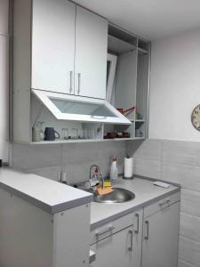 eine Küche mit weißen Schränken und einem Waschbecken in der Unterkunft Apartman Park Kragujevac in Kragujevac