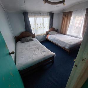 a room with two beds and two windows at Pies a tierra in Coihaique