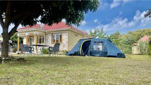 a blue tent in the yard of a house at Lake District Homestay in Rubirizi