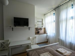 a white room with a bed and a tv on the wall at Penzión Záruby in Smolenice