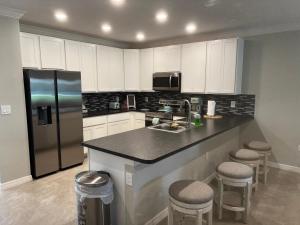 a kitchen with a sink and a refrigerator and stools at Luxurious Farm Style House in Kissimmee