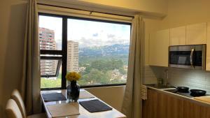 a kitchen with a table and a large window at Unique Studio Apartment in the heart of Guatemala City in Guatemala