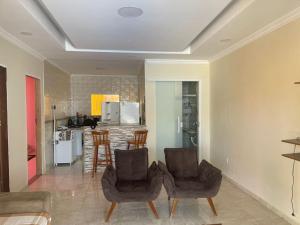 a living room with two chairs and a kitchen at Casa de buzios in Búzios