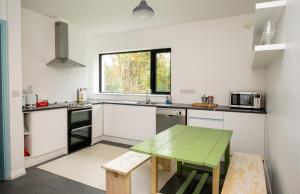 a kitchen with white counters and a green table at Lakehouse Inchiquin in Droíchead an Chláir