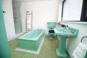 Lakehouse Inchiquin في Droíchead an Chláir: حمام مع حوض استحمام أزرق ومغسلة