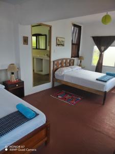 a bedroom with two beds and a mirror at Hospedaje Algarrobo Machalilla in Machalilla