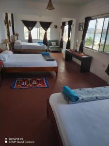a hotel room with two beds and a living room at Hospedaje Algarrobo Machalilla in Machalilla