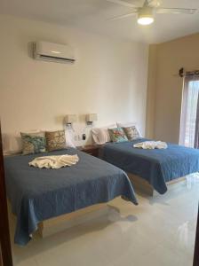 a bedroom with two beds with blue sheets and a fan at Villanueva Suite’s in Chacala