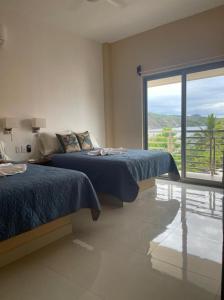 a bedroom with two beds and a large window at Villanueva Suite’s in Chacala