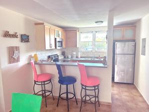 a kitchen with three bar stools in front of a counter at Come, Enjoy & Relax Bosque del Mar 1 Rio Grande, PR in Rio Grande