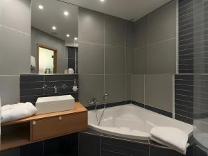 La salle de bains est pourvue d'une baignoire, d'un lavabo et d'un miroir. dans l'établissement Hotel Myrtilles, à Vielsalm
