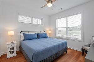 a bedroom with a blue bed and two windows at Charming Duplex Retreat in Old Town Manchester, VA in Richmond