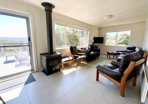 a living room with a fireplace and a couch and chairs at Central Beach house on Chandos in Eden