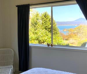 a bedroom with a window with a view of the water at Central Beach house on Chandos in Eden