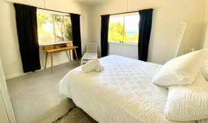 a bedroom with a bed and a desk and windows at Central Beach house on Chandos in Eden