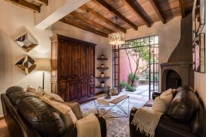 a living room with a leather couch and a fireplace at 3BR Garden Home with Rooftop & Garage in Centro San Miguel de Allende in San Miguel de Allende