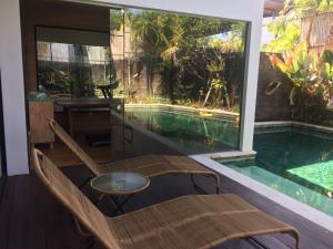 a room with a pool and a table and a chair at The Kesari Luxury Villa in Sanur