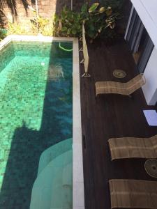 a swimming pool next to a wooden deck at The Kesari Luxury Villa in Sanur