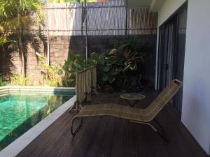 a wooden deck with a bench next to a swimming pool at The Kesari Luxury Villa in Sanur