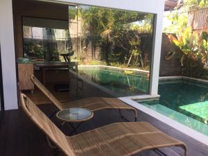 a room with a pool and a bench and a table at The Kesari Luxury Villa in Sanur