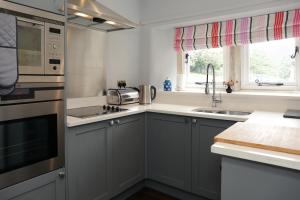 a kitchen with gray cabinets and a sink at The Old Cooling House in Summer Bridge