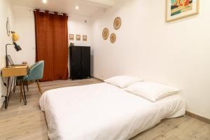- une chambre avec un grand lit blanc et un bureau dans l'établissement Nîmes Centre - A 5 minutes des Arènes, à Nîmes