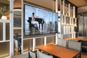 a woman sitting at a piano on a screen in a restaurant at NH Collection Olomouc Congress in Olomouc
