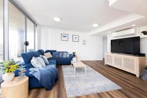 uma sala de estar com um sofá azul e uma televisão em Shores Unit 201 em Forster