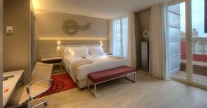 um quarto de hotel com uma cama, uma secretária e uma janela em NH Collection Porto Batalha em Porto
