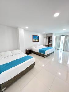 two beds in a room with white floors at Hotel AguaMarina Rodadero Santa Marta in Gaira