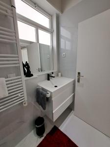 baño blanco con lavabo y ventana en CANTINHO DAS FIGUEIRAS en Nazaré