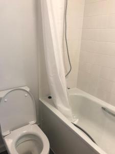 W łazience znajduje się toaleta oraz wanna z zasłoną prysznicową. w obiekcie Double Room close to Central London- Females Only w Londynie