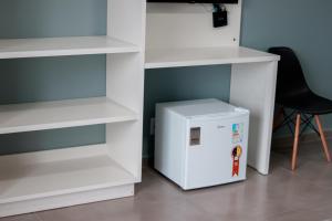 a white refrigerator sitting next to white shelves at Pousada da Bia Praia in Penha