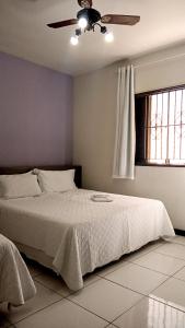 a bedroom with a bed with a ceiling fan at Pousada Colonial in Macaé