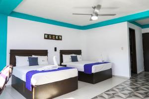 Duas camas num quarto com paredes azuis e brancas em Pa´Xa Mama Hotel Boutique em Cancún